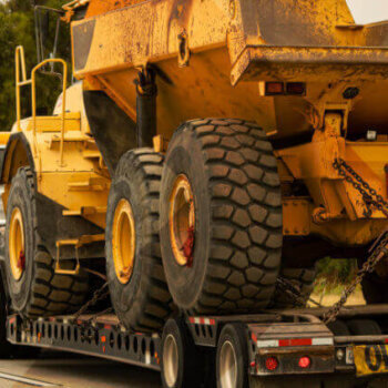 Flatbed hauling a tractor.