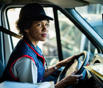 Woman in a van with a hat on and a blue and red vest