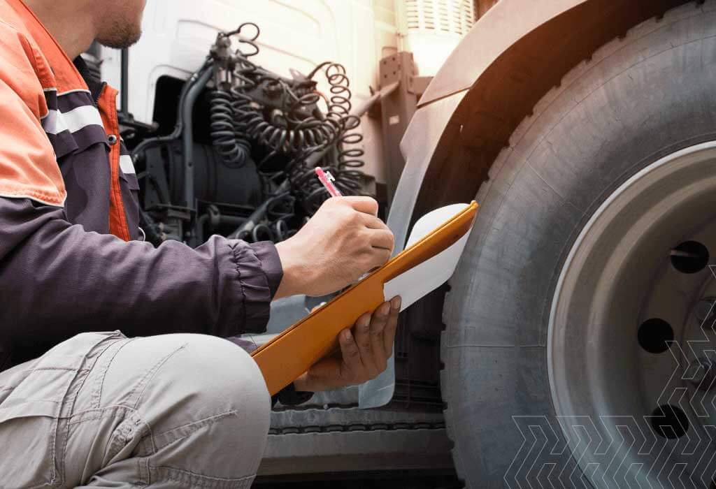 man inspecting a semi-truck and writing on a clipboard